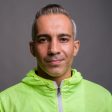 Studio shot of handsome Persian man with gray hair wearing neon green raincoat against gray background